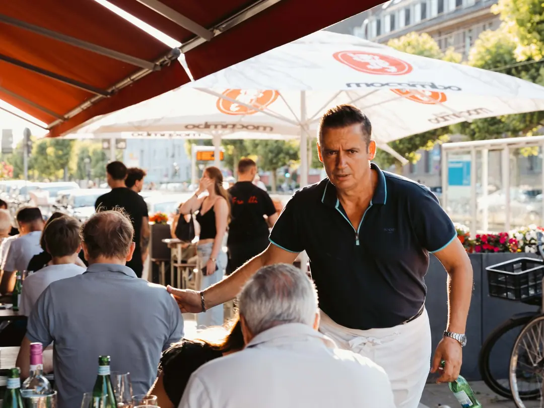 Gastgeber begrüßt Gäste auf der Terrasse der Pizzeria Fratelli in Düsseldorf-Oberkassel