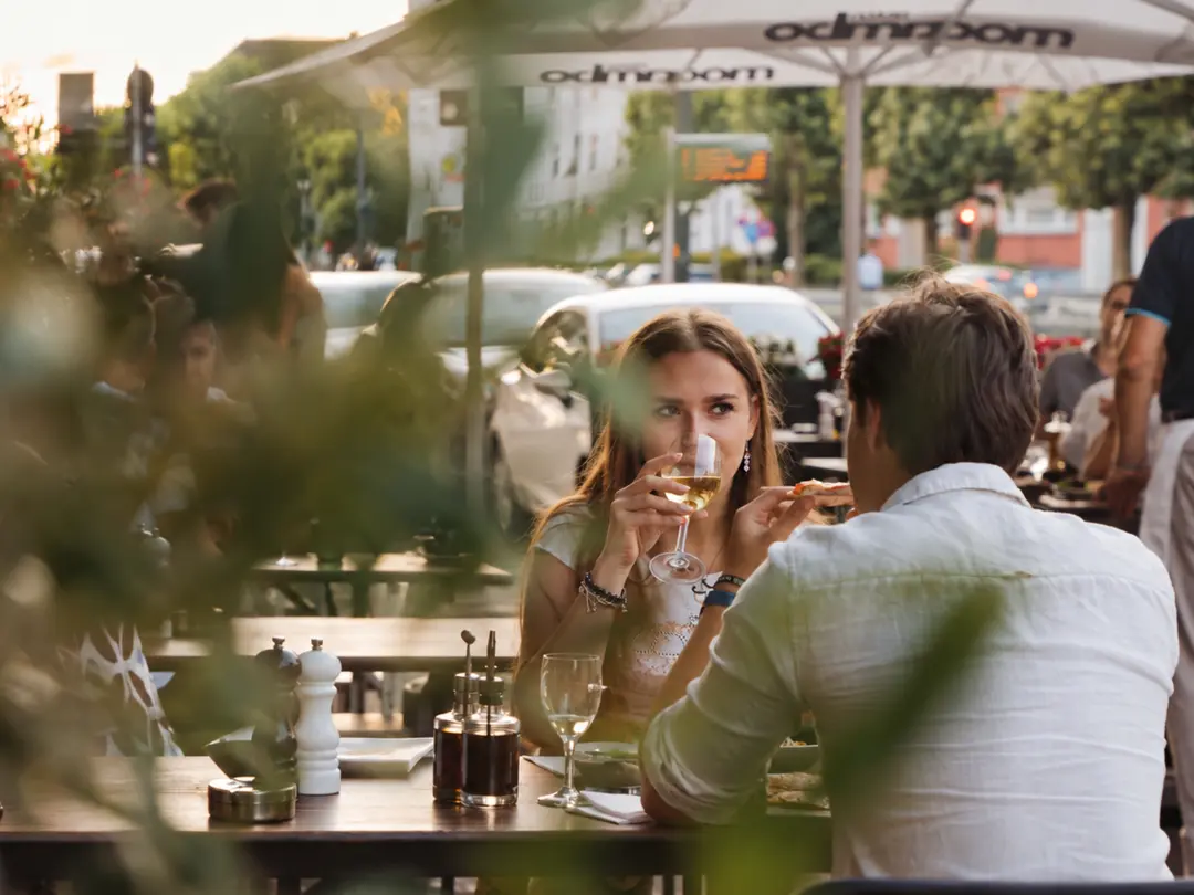 Gäste genießen Wein und Pizza auf der Terrasse der Pizzeria Fratelli